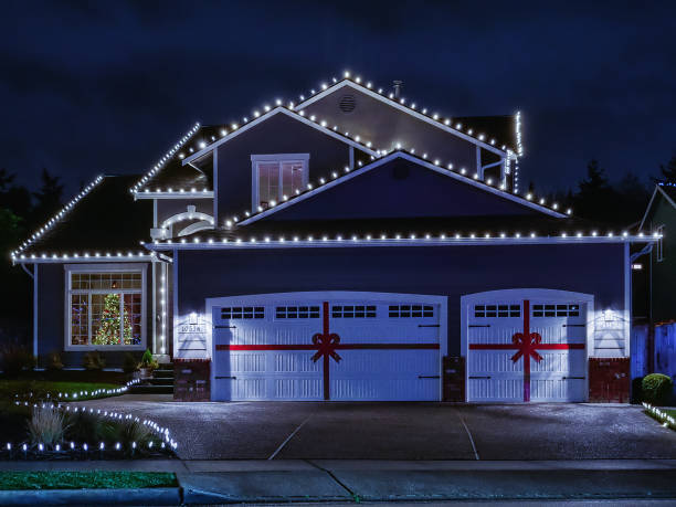 Warm-white holiday lights along the roof line and red ribbon bows on the garage doors of a Stateline home at twilight