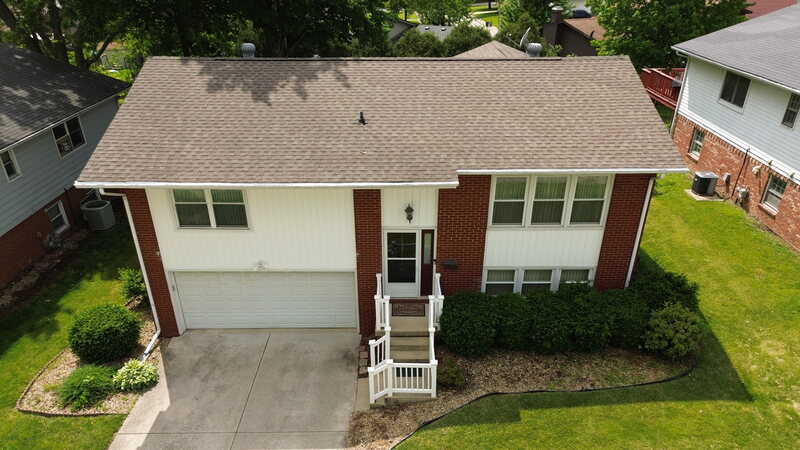 Aerial of a Decatur IL raised ranch before siding replacement, old white siding on the gable ends and over the garage with a red brick body