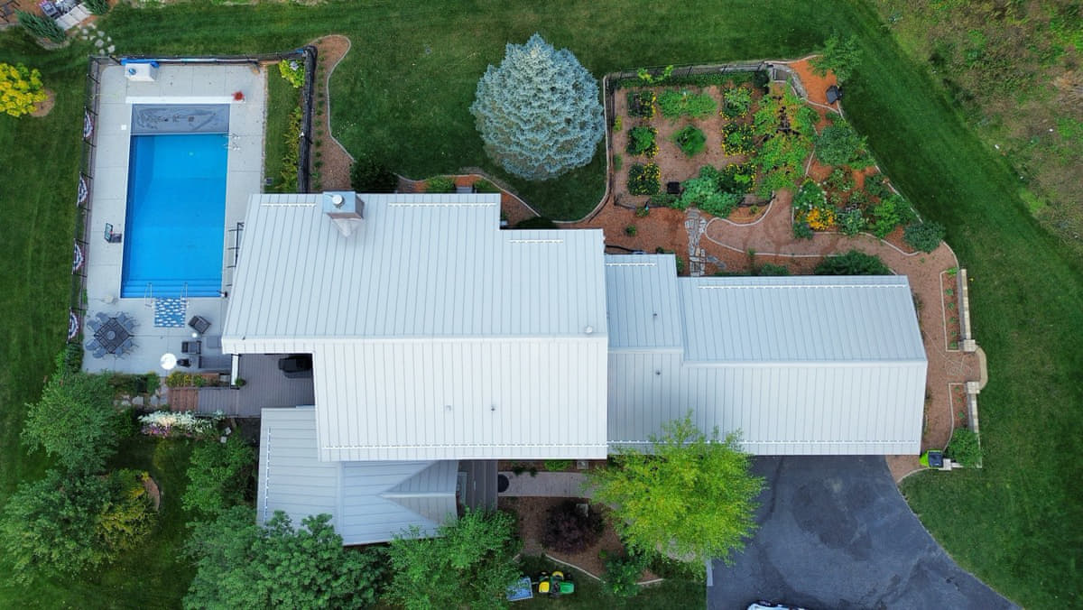 Same Edgerton, WI ranch-style home from the same drone vantage after a new gray standing-seam metal roof and seamless aluminum gutter installation