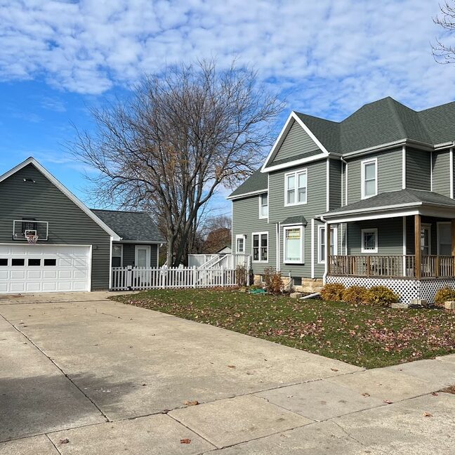 Finished siding replacement with sage-green lap siding and white trim on a two-story home in northern Illinois