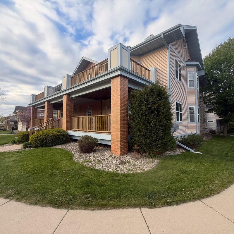 Finished multi-family siding replacement with tan lap siding, blue-grey accents, and white trim in northern Illinois