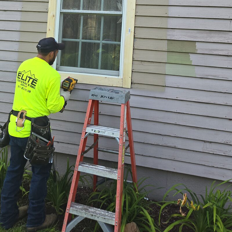 Elite Contracting Group team member repairing the wood trim around a window during a siding repair in Belvidere IL