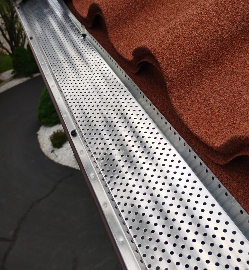Perforated aluminum gutter guard over a seamless gutter on the terracotta stone-coated metal tile roof in Brookfield WI