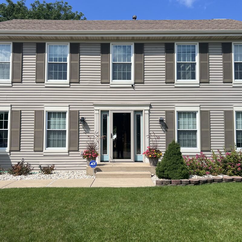 Completed asphalt shingle roof replacement on a two-story home in Rockford IL with light gray shingles and taupe siding