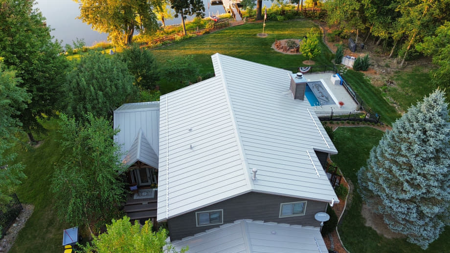 Aerial view of a white standing seam metal roof on a Wisconsin lakefront home installed by Elite Contracting Group
