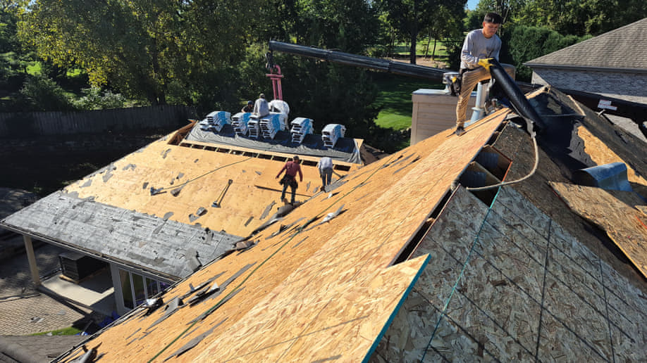 Aerial view of an Elite Contracting Group crew working a Wisconsin roof replacement, bundles staged on the bare deck with the conveyor lift in position